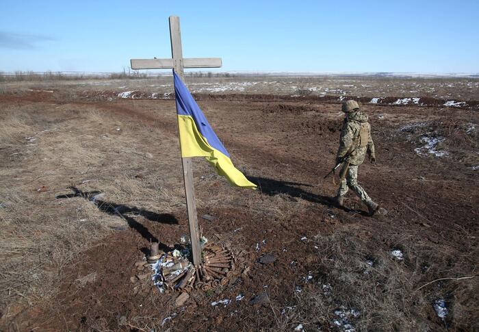 A Ukrainian soldier walks past a self made memorial to late soldier-mates in Svetlodarsk outside Donetsk, on March 12, 2022. (Photo by Anatolii Stepanov / AFP/ via ANSA)